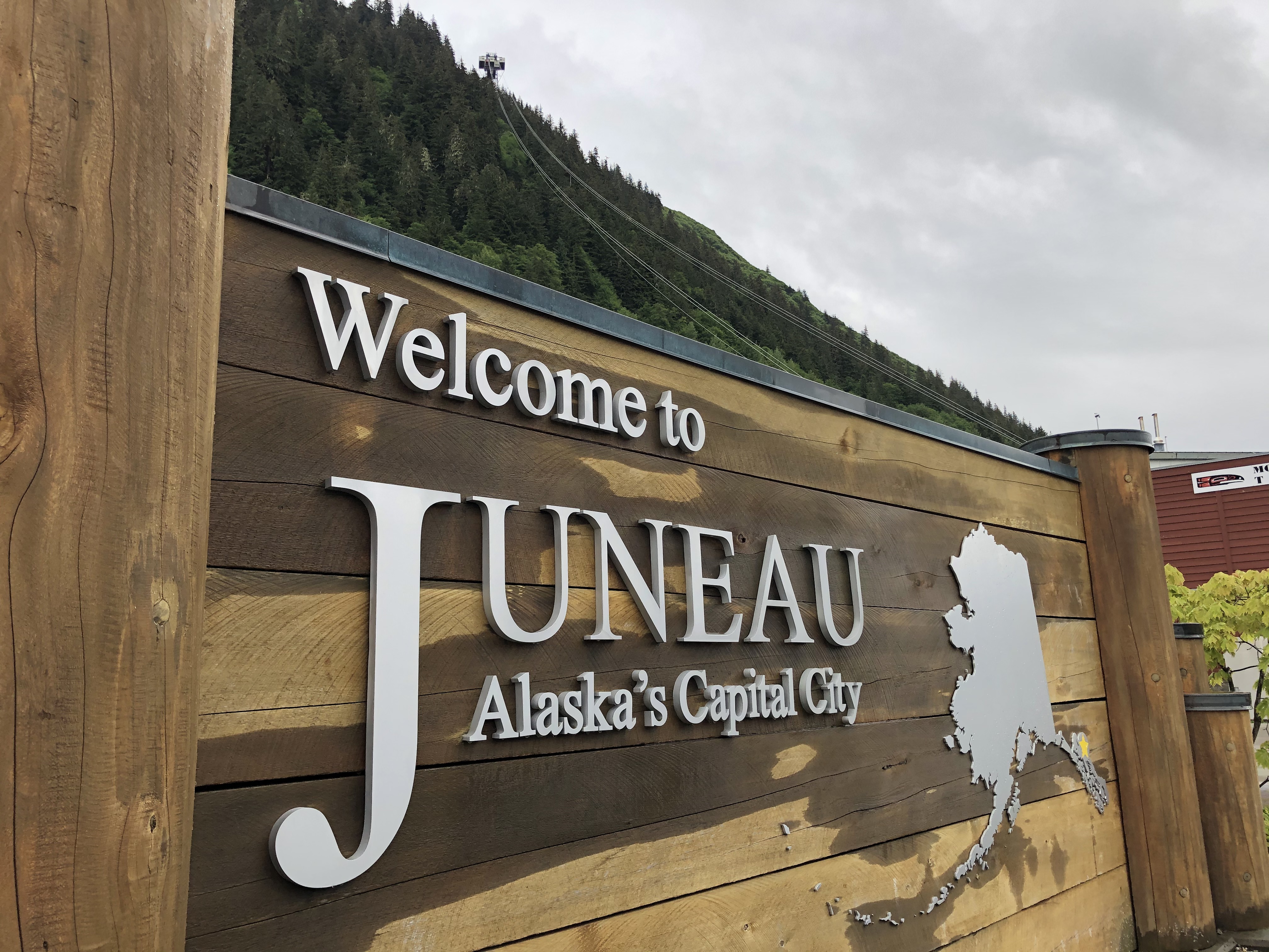 The wood of the Juneau welcome sign on the docks is wet from June rain