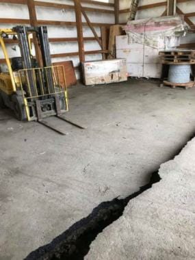 Photo of a large, offset crack in a warehouse floor.