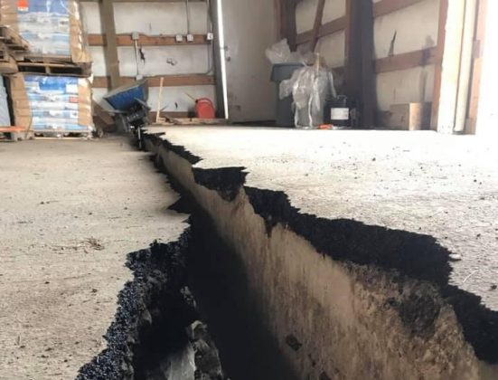 Photo of a large, offset crack in a warehouse floor.