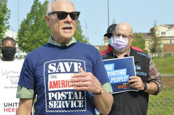 A group of men with signs and shirts supporting the postal service