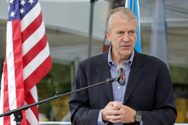 Sen. Dan Sullivan at a podium with a microphone and American flag