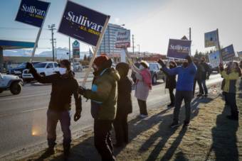 People gathered on the side of a road hold up Dan Sullivan campaign signs. Residents wave signs in support of Dan Sullivan at a busy intersection in Midtown Anchorage on Tuesday. (Jeff Chen/Alaska Public Media)