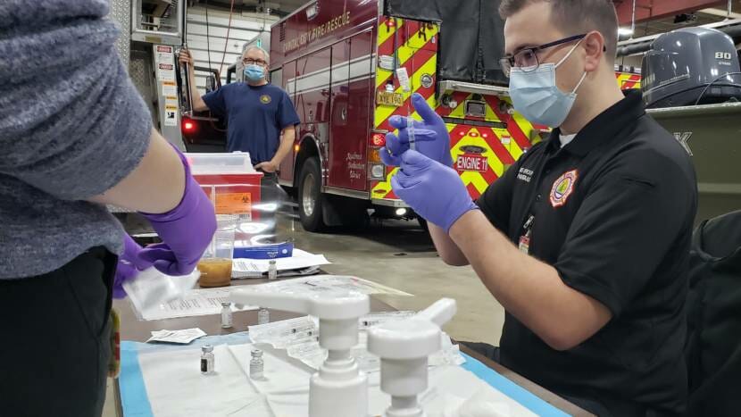 Capital City Fire/Rescue EMS Officer Andrew Pantiskas preps doses of Pfizer's COVID-19 vaccine as paramedic Lily Kincaid preps bandages at the downtown fire station in Juneau on Dec. 17, 2020.
