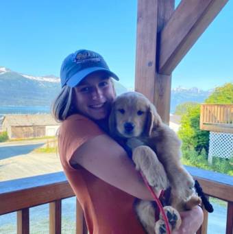 Jenae Larson holds a puppy on on the porch of the Port Chilkoot Distillery in Haines.