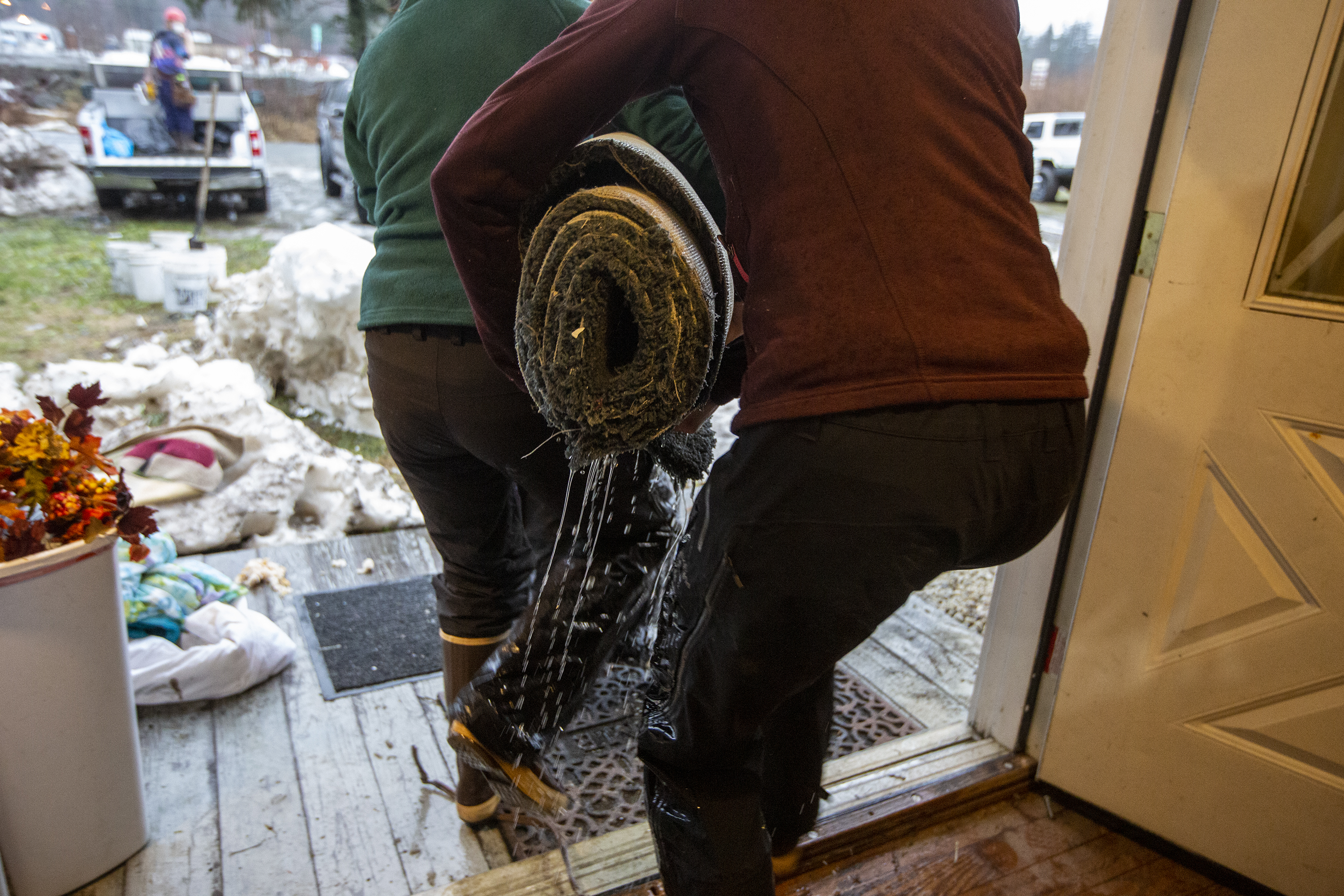People carry soaking carpet out of a flooded house in Haines, Alaska.