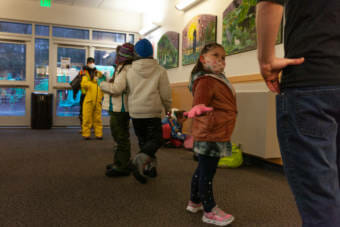 Avery Barnaby holds her "wings" out while standing in line as siblings Amara and Tanner Cooper play behind her on Thursday, Jan. 14, 2021, in Juneau, Alaska. Students are taught that when their wings are out, the tips shouldn't touch and they'll be far enough apart for social distancing at Sayéik Gastineau Community School. The school resumed in person learning after holding on remote classes for months due to the COVID-19 pandemic. (Photo by Rashah McChesney/KTOO)
