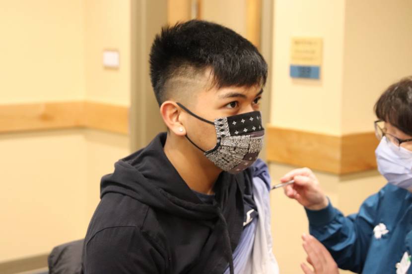 A teenage boy receives a dose of the COVID-19 vaccine