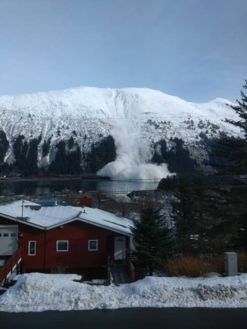 An avalanche cascading down a steep mountain into water