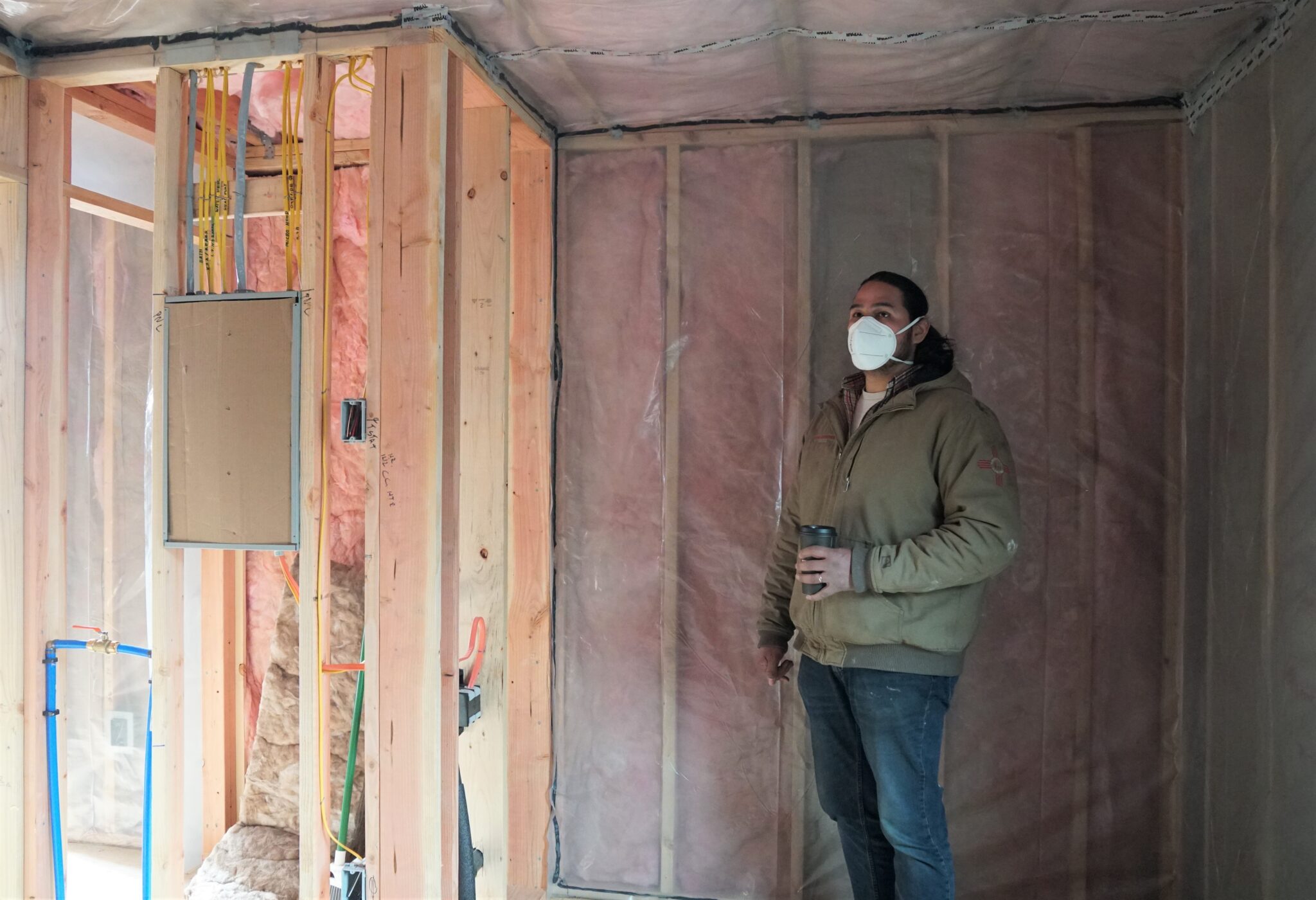 Co-owner of Sitka Construction Solutions, Derek James, points out the future bathroom in an unfinished “mini home.” (KCAW/Erin McKinstry)