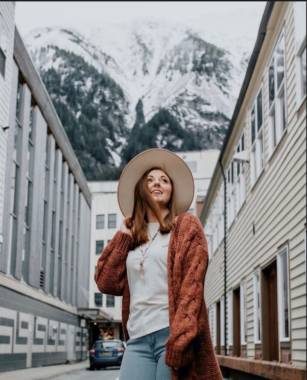 Photo shows woman in hat in front of mountains