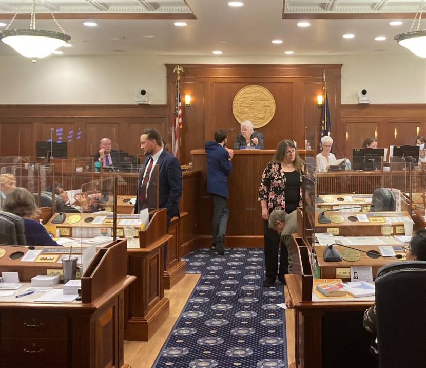 Alaska House members talk during a break in the debate on whether to draw from the Constitutional Budget Reserve in the Alaska State Capitol in Juneau on June 15, 2021. Kodiak Republican House Speaker Louise Stutes is seated in the center on the podium. (Photo by Andrew Kitchenman/KTOO and Alaska Public Media)