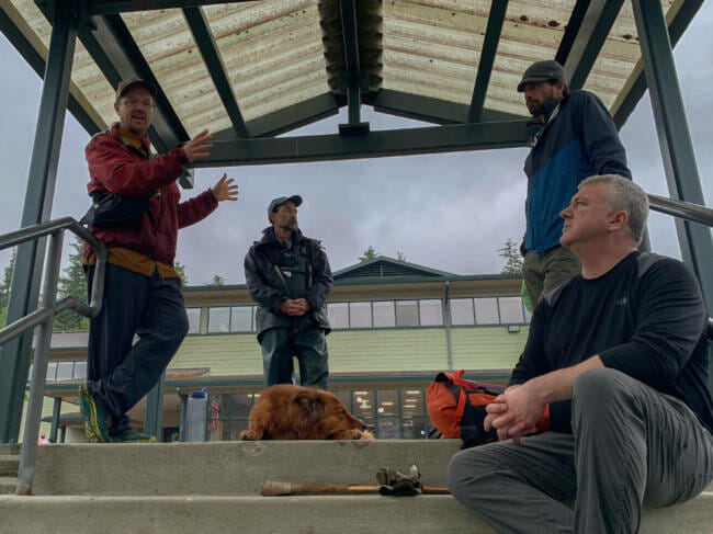 Geologist Bretwood Higman (left) talks about a potential landslide hazard above Lemon Creek, during a press event on Thursday, June 10 in the parking lot of Dzantik'i Heeni Middle School. He is joined by CBJ Emergency Programs Manager, Tom Mattice (far right) and other researchers from CBJ and the National Weather Service in Juneau. 