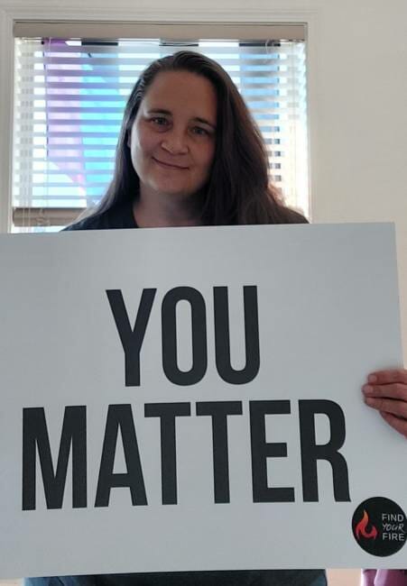 Juneau resident Casey DenAdel poses with a 'you matter' sign she displays in her window. 