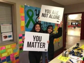 Two Juneau high school students pose with signs displaying positive messages during a 'Take a Time Out to Talk' event in 2020.