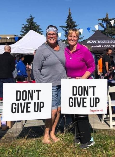 Timi Tullis and Melissa McCormick pose with 'don't give up' signs during an event at the University of Alaska Southeast.