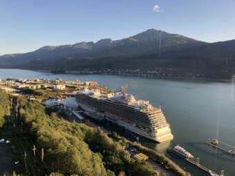 A view from above of a large cruise ship docked in Juneau with Douglas Island in the background