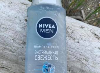 a shampoo bottle with Russian labeling lying on a piece of driftwood