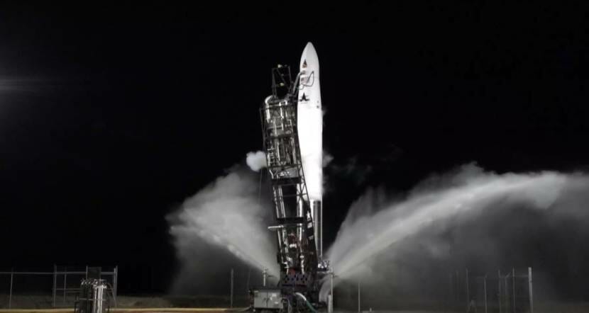 A rocket lifting off from a launch pad in the dark