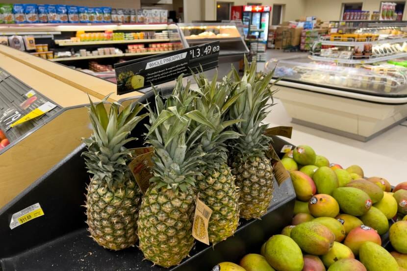 Pineapples and mangoes on display in a grocery store produce section