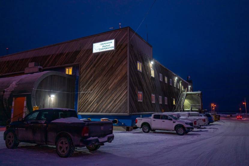 A large, two-story building with wooden siding and a sign that says Ukpeaġvik Iñupiat Corporation