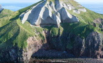 A steep, conical hill with cliffs at its base.