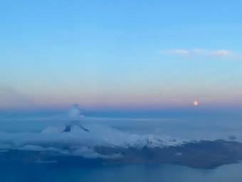 A volcano with a small plume above it, seen from an airplane at either twilight or dawn