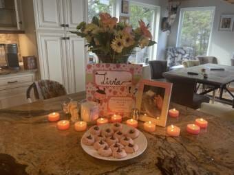 A plate of cookies, lit candles, a card, brightly colored flowers and a photo of a baby are arranged on a table as a shrine in memory of pregnancy loss.