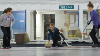 A woman preparing to slide a curling stone.