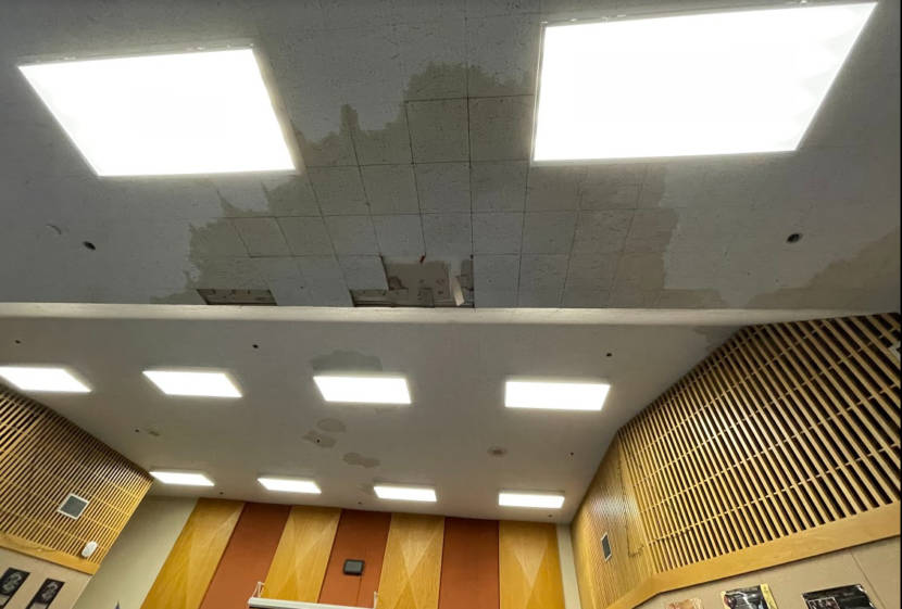 Large water marks and missing tiles in a classroom ceiling