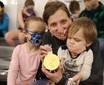 A woman and two small children posing with an Olympic gold medal