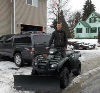 A man on an ATV with a snow plow attached