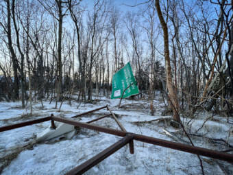 A large highway sign knocked over and blown into the woods