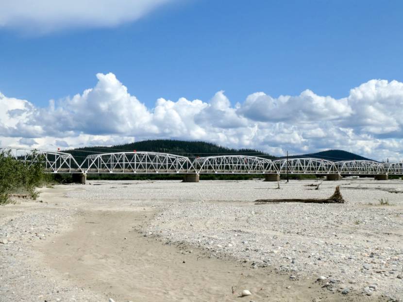 A long, steel truss bridge over a wide river bed. The bridge is on the route that the ore trucks would take.