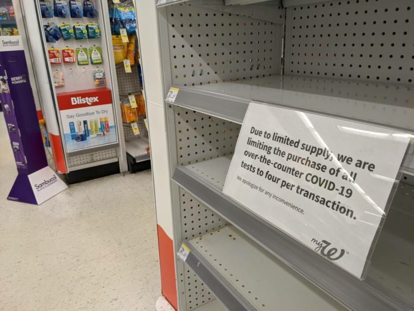 Empty store shelves with a note saying the store is limiting purchases of rapid covid tests due to lack of supply.