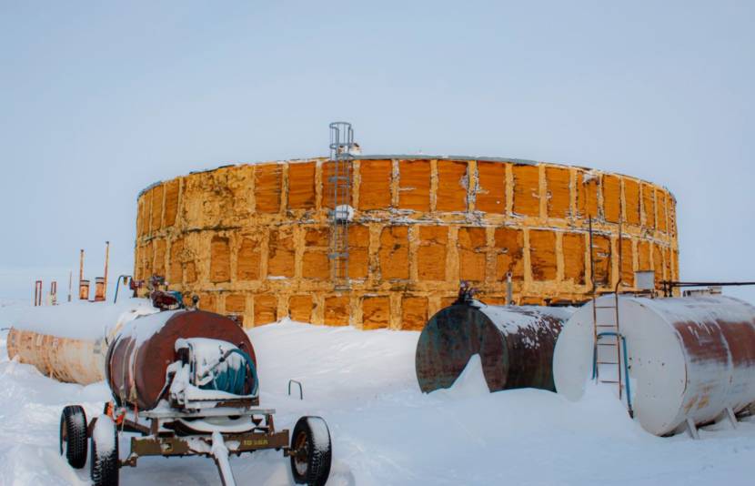 A large, yellow cylindrical water tank in the snow