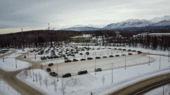 Seen from above, a long line of cars snaking through a parking lot at a covid testing site