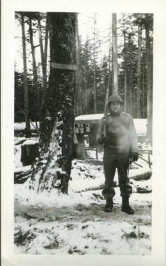 A faded old photo of a soldier standing in a snowy forest, holding a rifle on his shoulder
