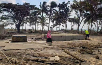 Two people in a damaged area of a resort covered in ash and mud