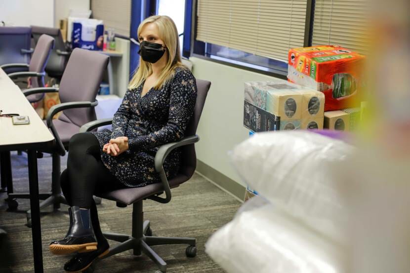 A masked woman sitting in a desk chair in an office