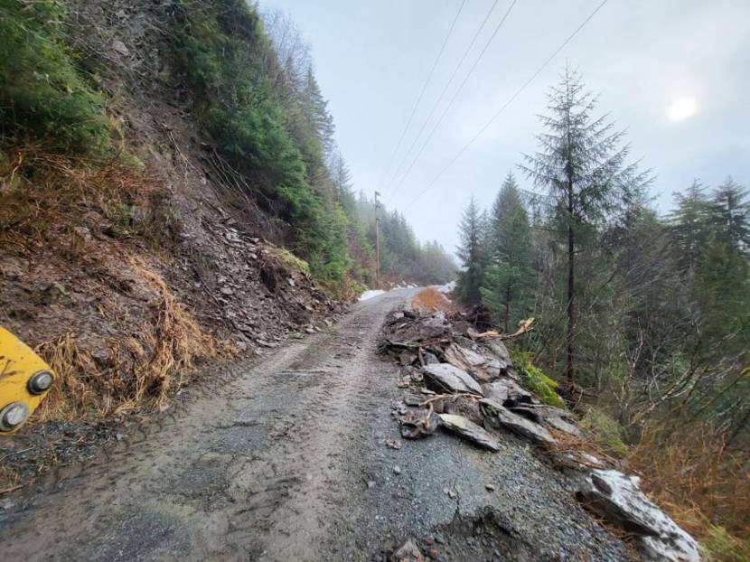 A gravel road with piles of rock along the side after a landslide was cleared