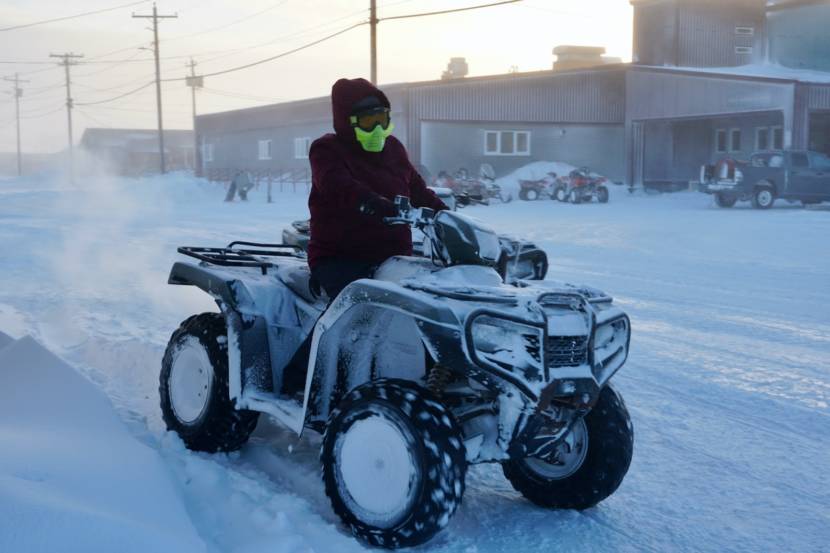 A woman driving and ATV on a snowy street
