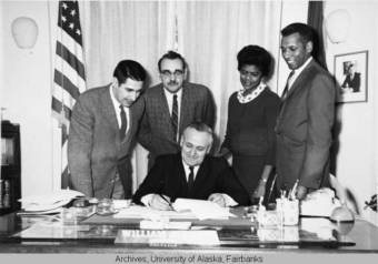 Photograph of Governor Egan signing the Human Rights Act. Identified are left to right Sen. Mike Gravel, Dick Hedberg-AFL-CIO, Maria G. Bowman and Willard Bowman-NAACP. (Photo courtesy of the William A. Egan Papers, Elmer E. Rasmuson Library, University of Alaska Fairbanks, (UAF-1985-120-555)