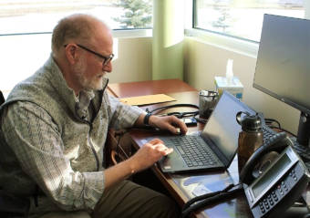 A man sitting at a desk, typing on a laptop