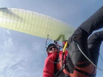 A man in red hanging from a yellow paraglider