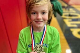 A smiling child holding up a medal