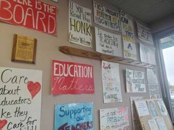 Paper, handmade signs with slogans like "education matters" and "supporting our teachers" taped to a wall