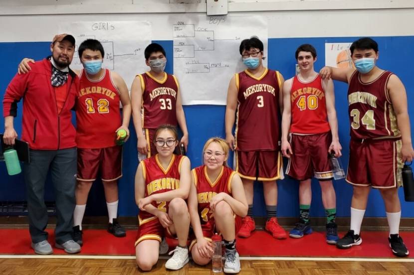 A 7-player coed basketball team poses for a photo in a gym