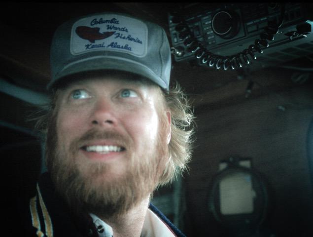 An old color film snapshot of a bearded man in a baseball cap