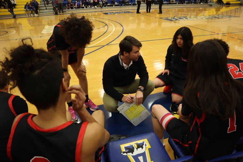High school basketball players gathered around their coach