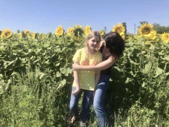 A mother and daughter embrace in a field of sunflowers